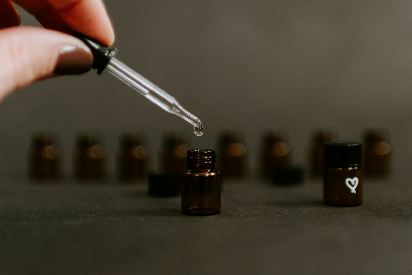 Dropper held over a small dark essential oil bottle